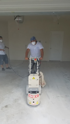 Two men in a garage with a floor scruber