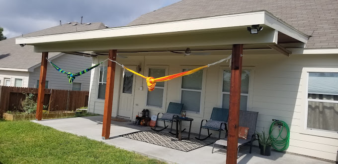 A covered patio with chairs and a hammock